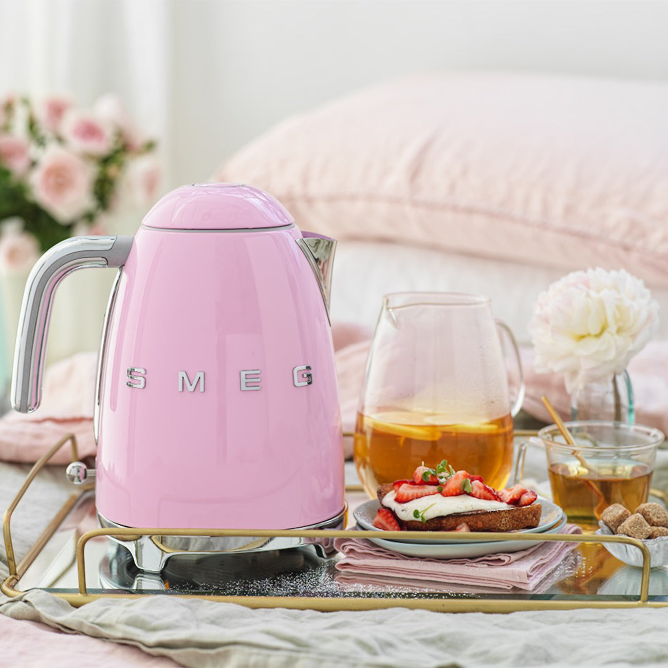 Pink Smeg kettle on a table with tea and cake