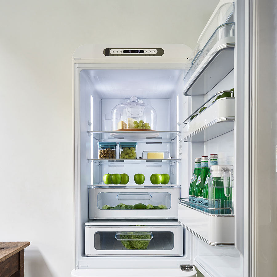Open Smeg refrigerator with various items inside on a white background