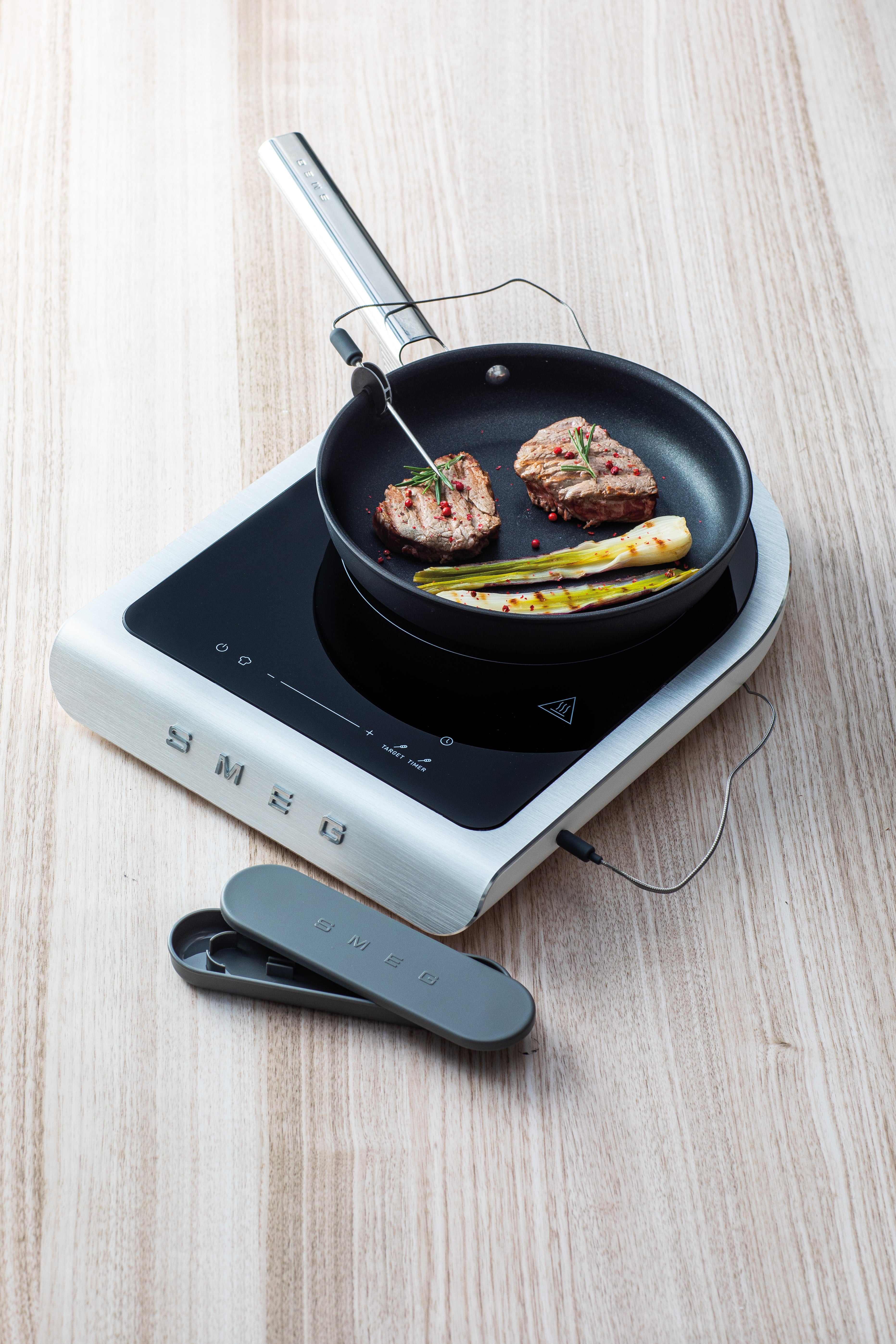 Portable induction hob with a frying pan on a wooden surface